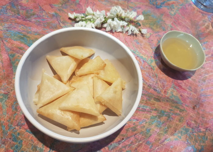 Bol a fond plat contenant des samosa grappe de fleur d'accacia coupelle contenant du sirop