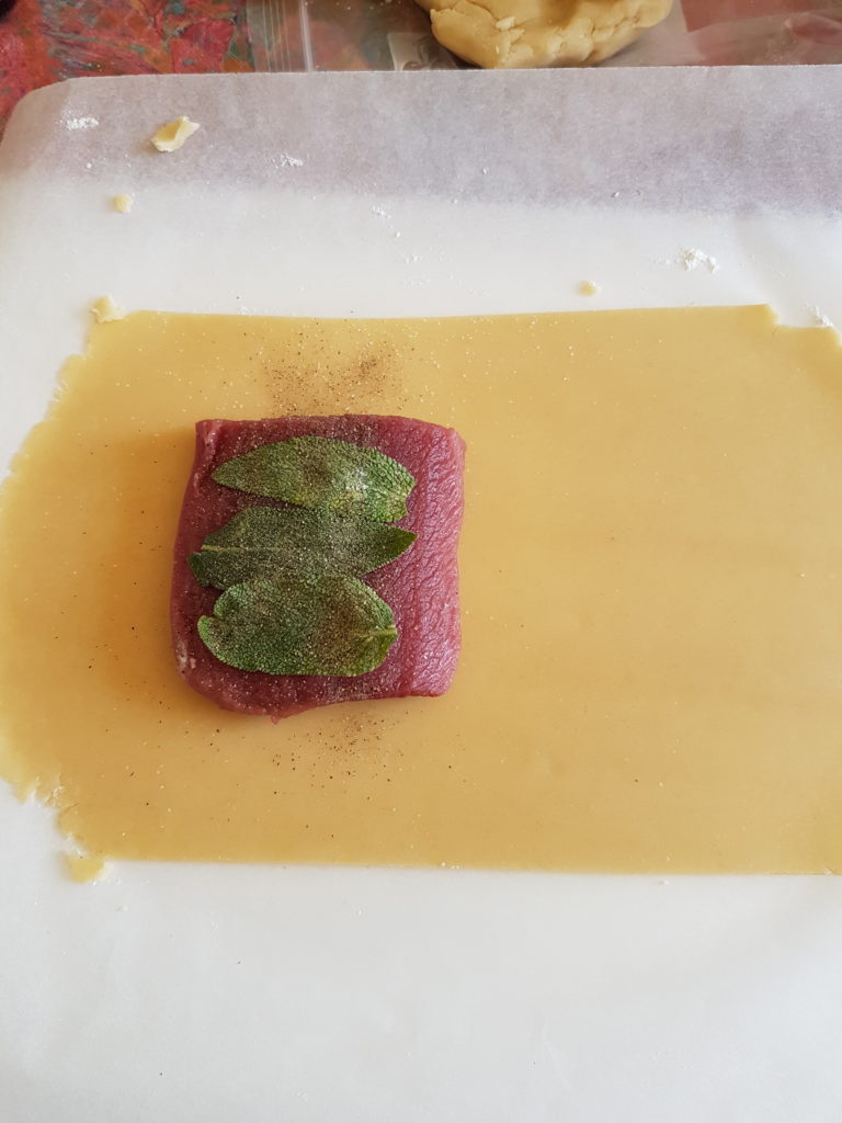 abaisse de pate brisée piece de viande avec feuilles de sauge feuille de papier sulfurisé