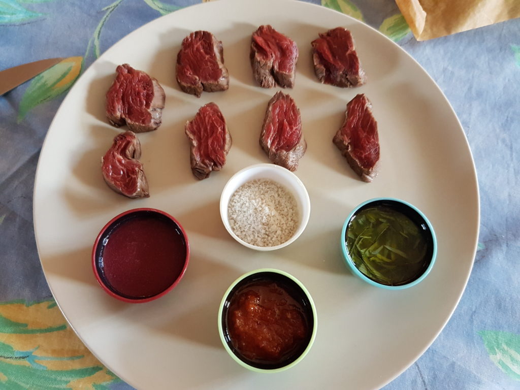 morceaux de viande de boeuf avec trois coupelles de condiments une coupelle de sel