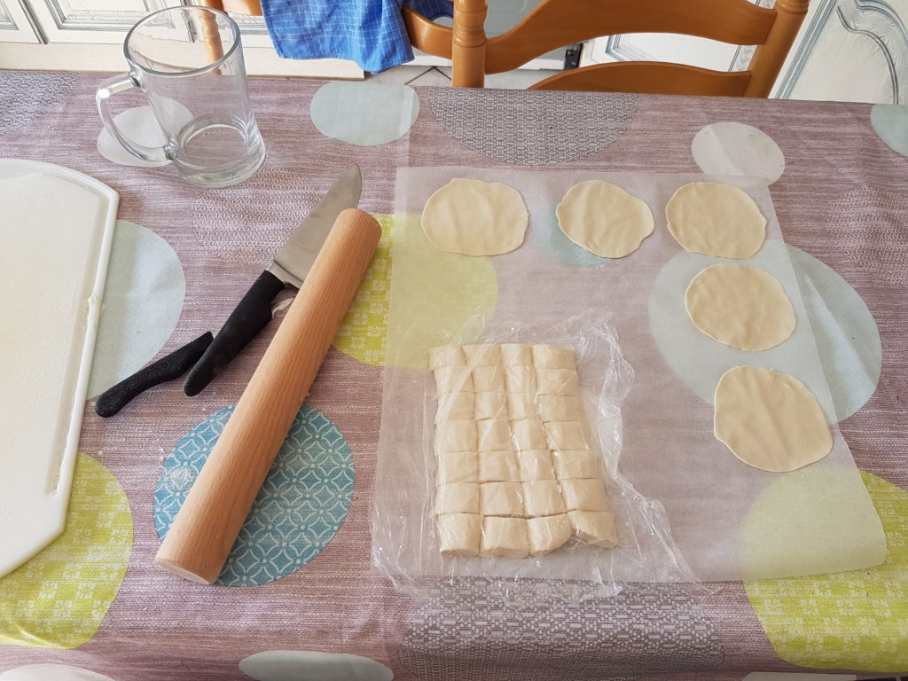 table de cuisine rouleau a patisserie pate en blocs sous film alimentaire sur papier sulfurise ronds de pate étalés