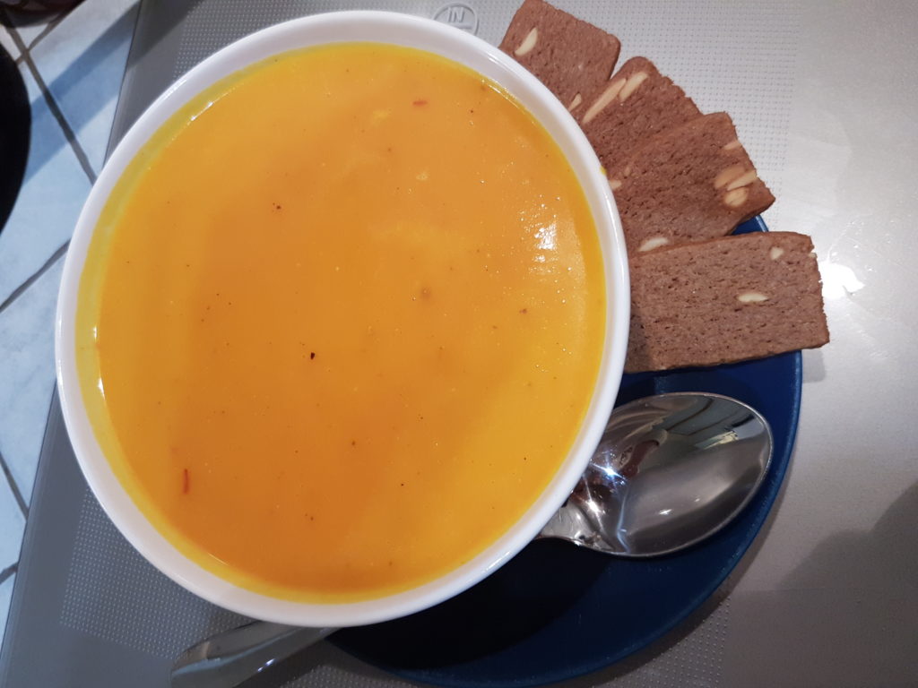 bol de soupe de potimarron avec speculoos sur le bord d'une assiette