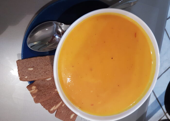 bol de soupe de potimarron avec speculoos sur le bord d'une assiette