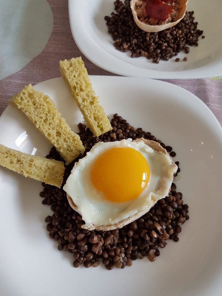 oeuf au plat dans une coque sur des lentilles et des mouillettes vertes sur le coté photo portrait avec autre coque sans oeuf en arriere plan