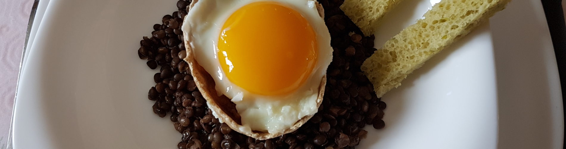 oeuf au plat dans une coque sur des lentilles et des mouillettes vertes sur le coté photo paysage