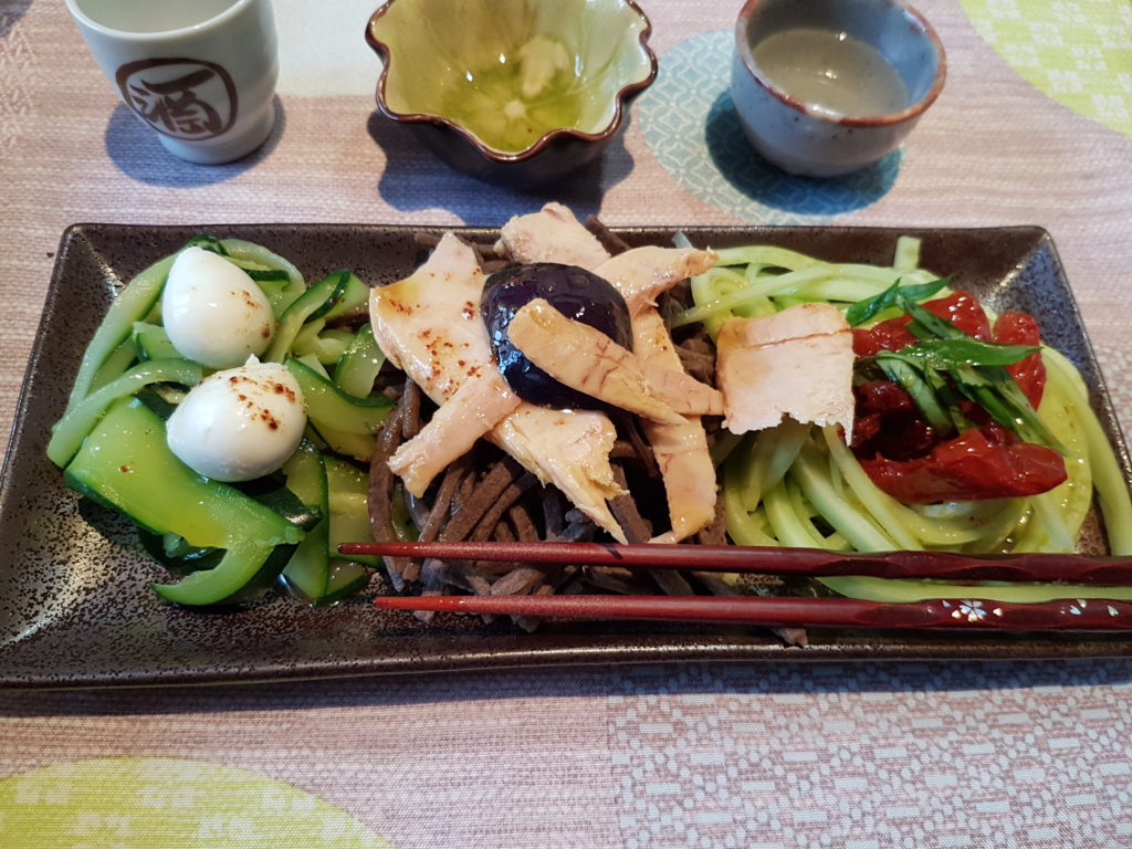 legumes nouilles soba et garniture sur une assiette marron rectangulaire une sauce avec des particules de piment repartie sur l ensemble