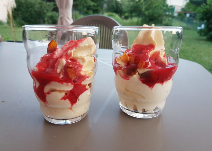 deux verres fantaisie sans dessin contenant une mousse blanchatre légèrement orangée avec de petits morceaux de fruit orange et du coulis de fruit rouge