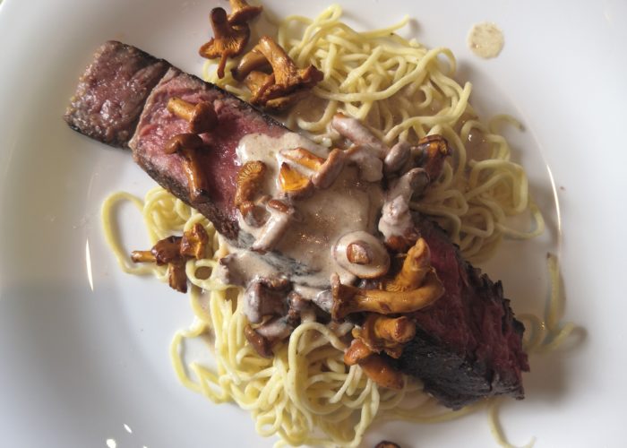 piece de boeuf cuite, spaghetti et champignons sur une assiette blanche