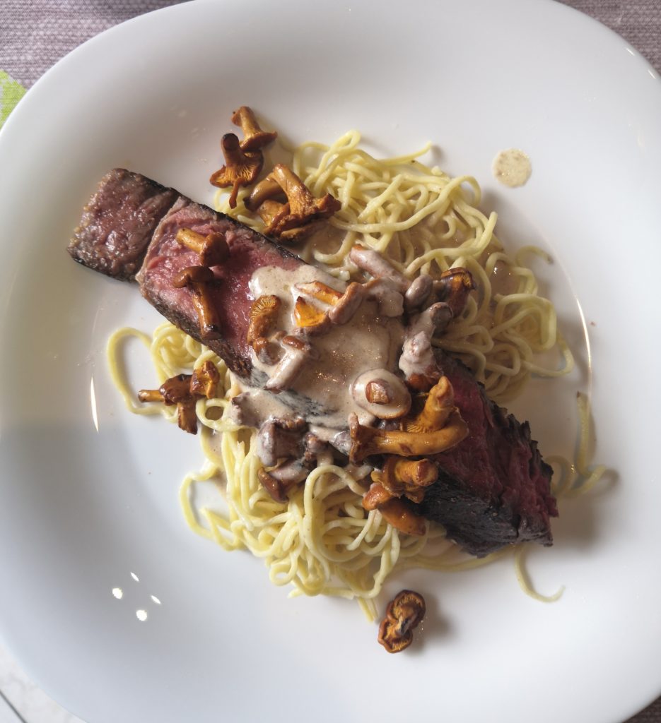 piece de boeuf cuite, spaghetti et champignons sur une assiette blanche