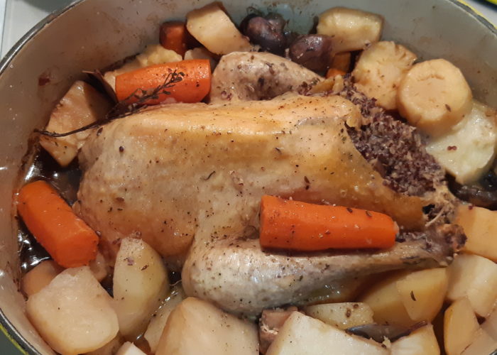 pintade cuite entourée de légumes dans une cocotte en fonte