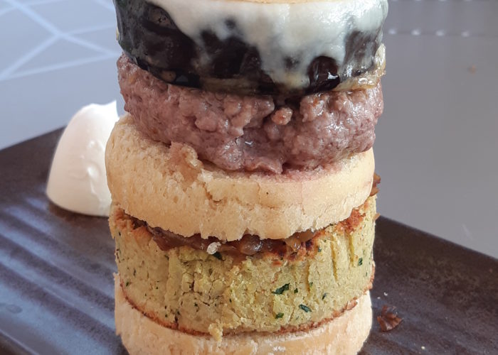 hamburger vertical en gros plan bun, falafel, une fine couche visible de confiture d'oignon, bun, une épaisseur similaire à celle d'un bun de viande hachée claire, un tranche d'aubergine large, de la mozzarelle fondue, bun