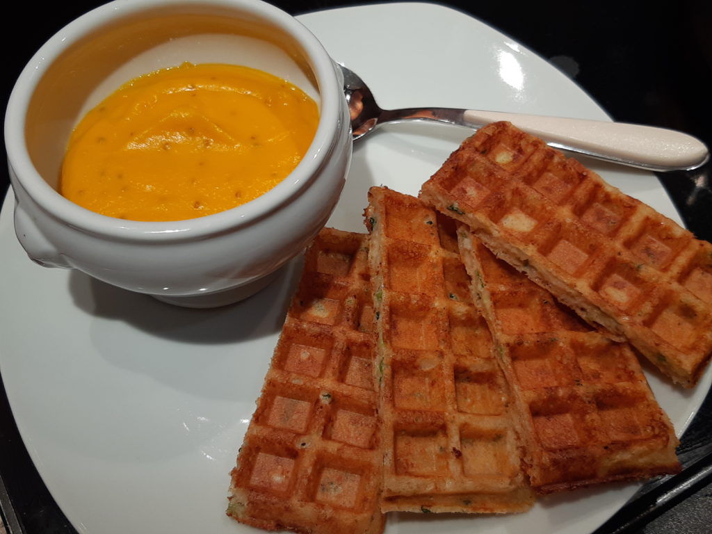 portions de gaufre sur une assiette avec un bol contenant une crème orangée