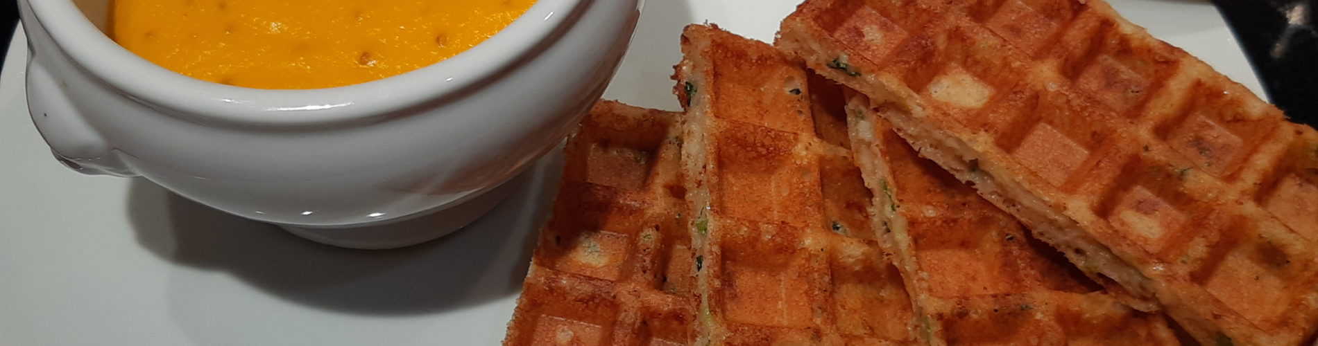 portions de gaufre sur une assiette avec un bol contenant une crème orangée