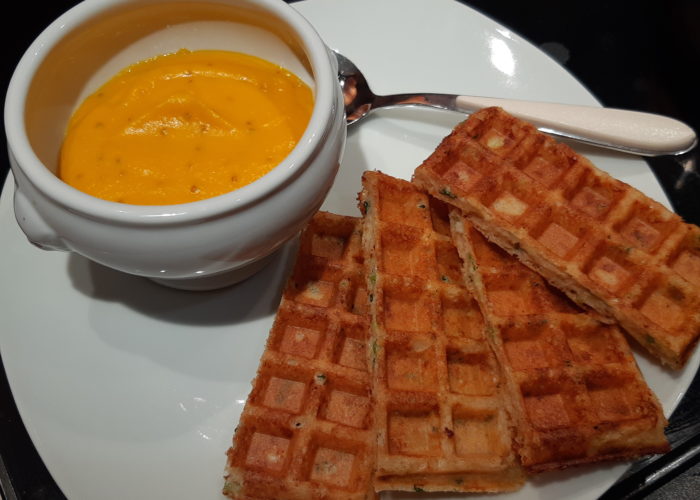 portions de gaufre sur une assiette avec un bol contenant une crème orangée