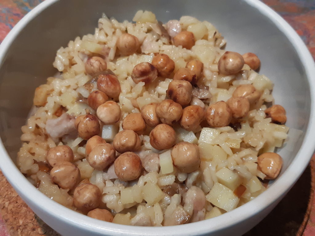 risotto contenant des légumes blancs et des morceaux de viande blanche recouvert de noisettes