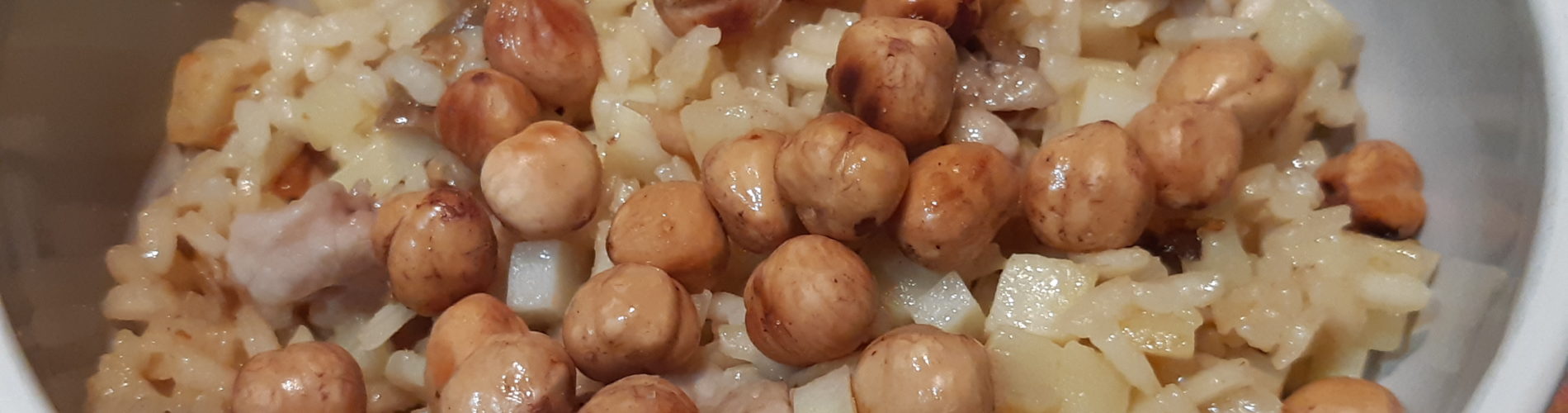 risotto contenant des légumes blancs et des morceaux de viande blanche recouvert de noisettes