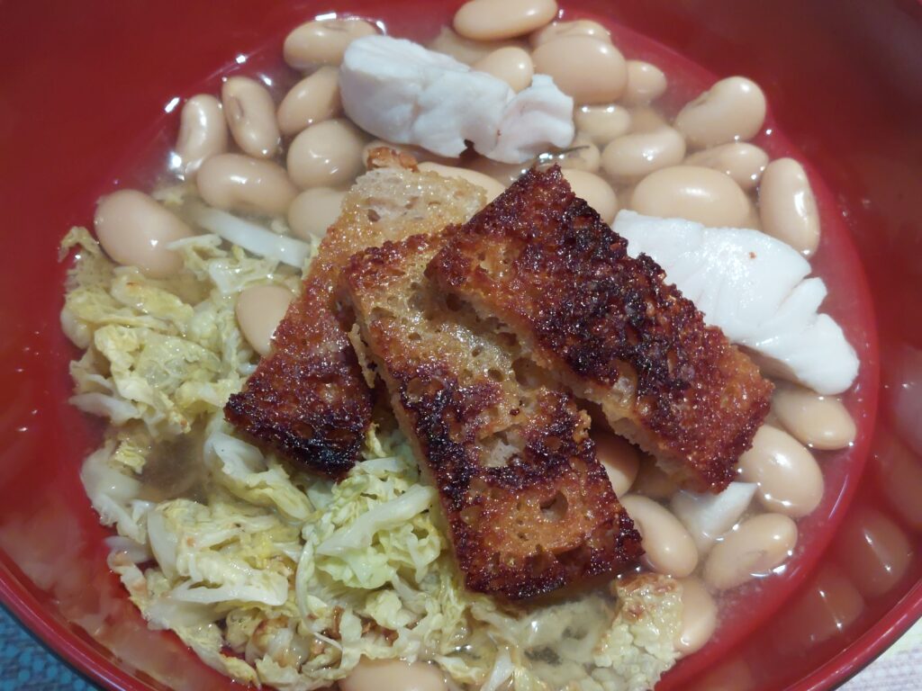 bouillon avec haricots chou et poisson blanc dans un bol rouge