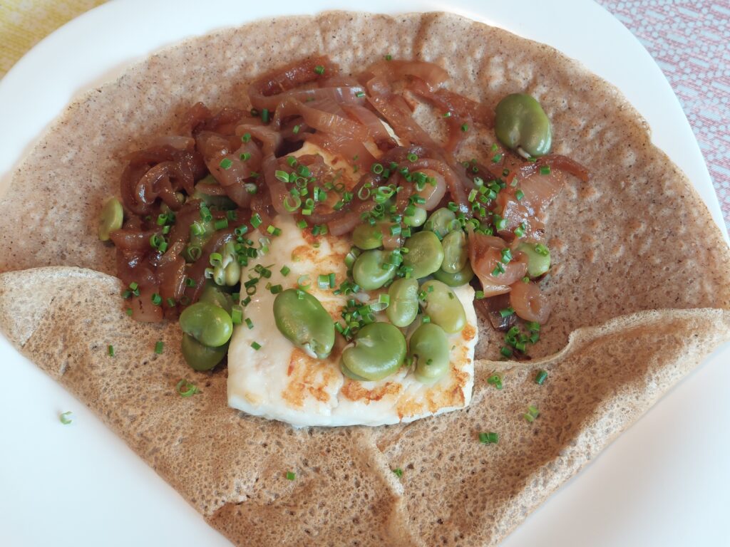 crepe garnie avec du poisson blanc de l'oignon et des feves