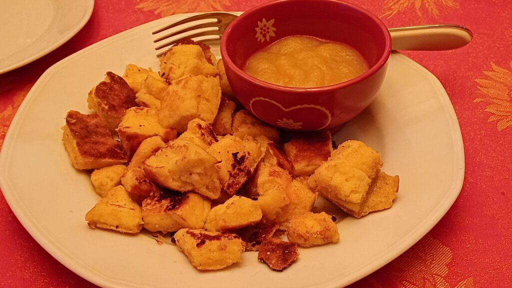 morceaux de Keiserschmarren sur une assiette avec un ramequin de compote