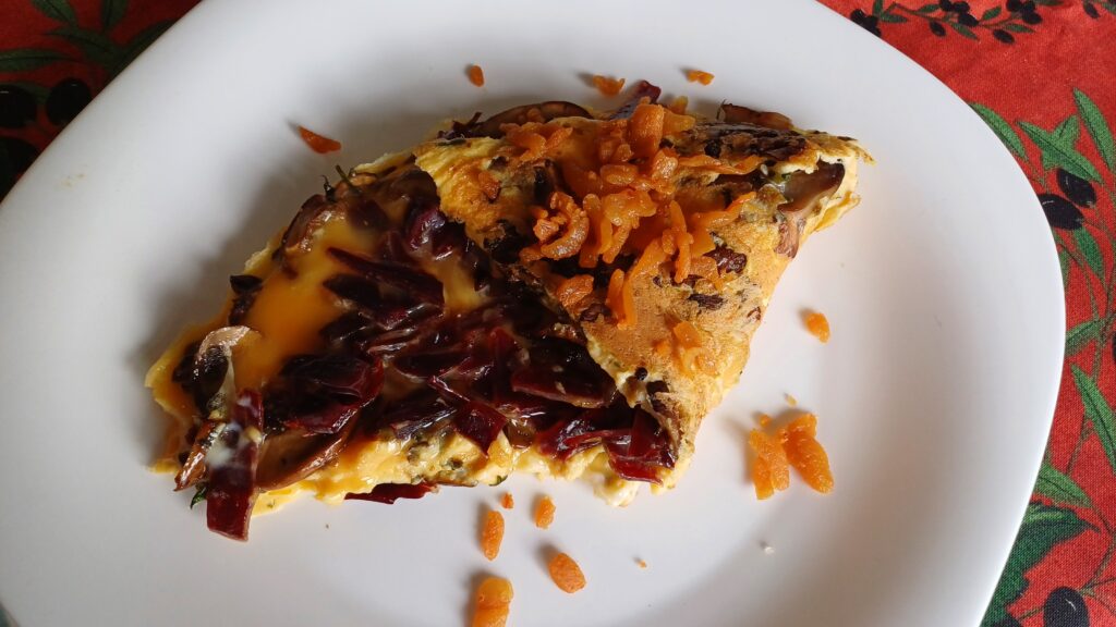 omelette baveuse garnie partiellement rabattue saupoudrée de petits morceaux de gras grillé