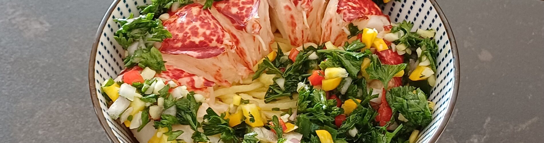 Queue de homard décortiquée avec de la verdure coupée fin dans un bol on voit des pates fines en dessous