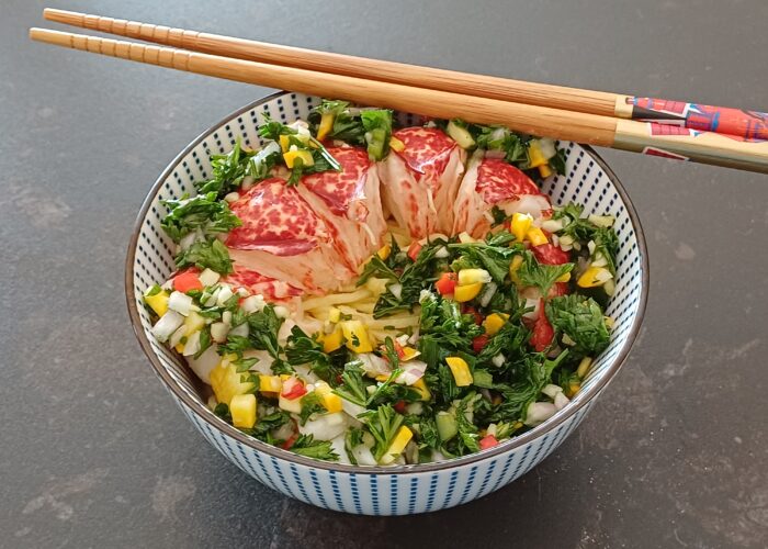 Queue de homard décortiquée avec de la verdure coupée fin dans un bol on voit des pates fines en dessous
